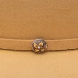 Close-up of a tan fabric with a decorative button featuring a flower design.
