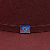 Close-up of a maroon hat with a blue and silver logo on a brown background